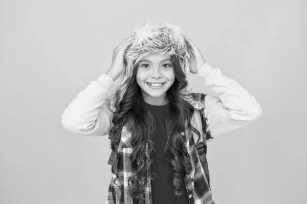 Winter season concept. Northern region fashion. Soft furry accessory. Warm hat for cold weather. Kid girl wear hat with ear flaps. Freezing here. Eskimo funny schoolgirl try on hat enjoy softness — Stock Photo, Image