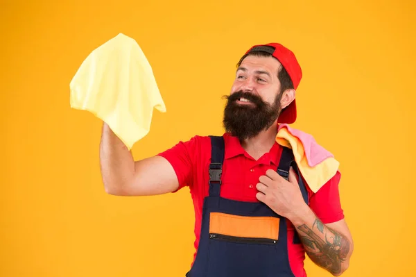 建設清掃サービスの後。家に明かりをつけなさい。男残酷な陽気なひげを生やした労働者のほこりのラグを拭く。掃除用品のコンセプト。簡単な洗浄のヒント。男は一片の布で働く — ストック写真