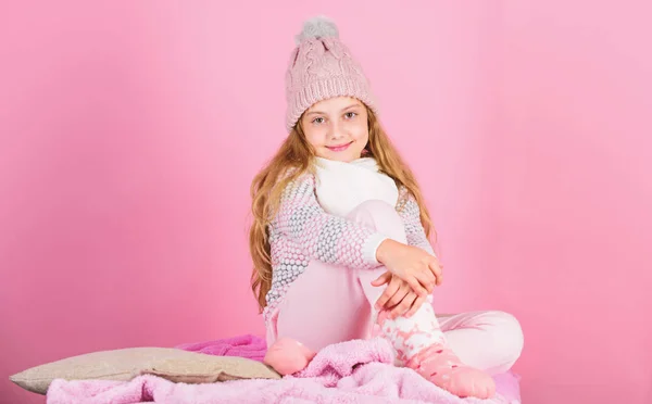 어린이의 긴 머리를 가진 따뜻 한 모직 모자는 따뜻 함을 즐긴다. 따뜻 한 옷 컨셉. 따뜻하고 편안 한 상태를 유지하 십시오. 따뜻 한 액세서리는 이번 겨울을 아늑하게 해 줄 것이다. 여자 애는 분홍빛 배경에 뜨개 질 모자를 쓰고 — 스톡 사진