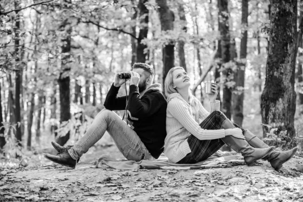 男子用望远镜和女人与金属杯享受自然公园。停车日期。一起在公园里放松。快乐的爱夫妇一起在公园里放松。夫妇在爱游客放松野餐毯 — 图库照片