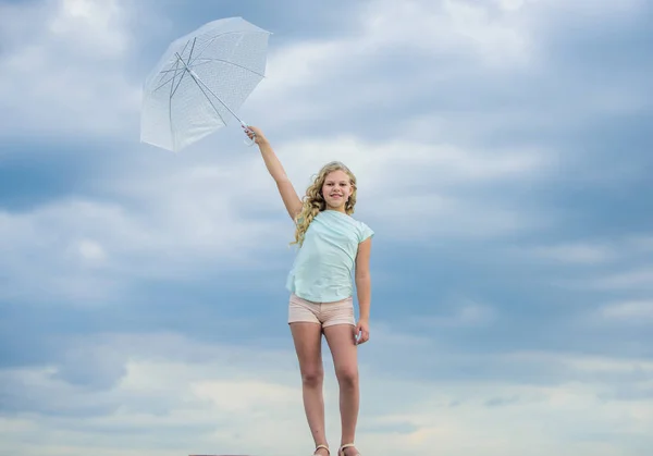 Carefree child outdoors. Weather forecast. Ready for any weather. Weather changing. Fresh air. Girl with umbrella cloudy sky background. Freedom and freshness. Anti gravity concept. Enjoying ease