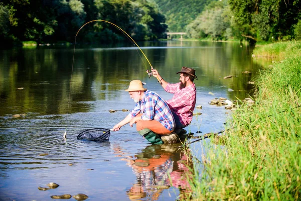 Uma isca giratória. passatempo de peixe de mosca de homens em camisa quadriculada. pesca da reforma. felizes pescadores amizade. Dois amigos a pescar juntos. Captura e pesca. aposentado pai e maduro barbudo filho — Fotografia de Stock