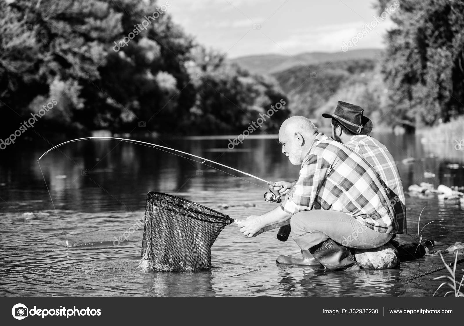 Beautiful evening riverside. Men riverside catching fish. Teaching fishing.  Sharing his secrets. Transferring knowledge. Friends spend nice time at  riverside. Experienced fisherman show tips to son Stock Photo by ©stetsik  332936230