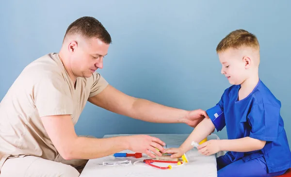 Servicio médico. Hombre doctor sentarse mesa herramientas médicas examinando niño pequeño paciente. Salud. Concepto de pediatra. El pediatra cuidadoso comprueba la salud del niño. Examen médico. Trabajador hospitalario —  Fotos de Stock