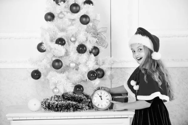 Новогодний отсчет. Девочка в шляпе костюм Санта держать часы взволнованные счастливое выражение лица подсчет времени до нового года. Новый план на последнюю минуту. Счастливого Рождества. Последняя минута до полуночи — стоковое фото