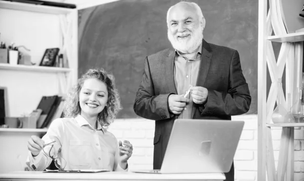 Divirtiéndose juntos. estudiante y tutor con laptop. chica estudiante feliz con tutor hombre en pizarra. aprobar el examen. sala de profesores. profesora sénior y mujer en la clase escolar. educación escolar moderna — Foto de Stock