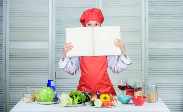 Concetto culinario. Amatoriale cuoco leggere ricette libro. La ragazza impara la ricetta. Prenota dal famoso chef. Migliorare l'abilità di cottura. Ricette del libro. Secondo la ricetta. Libro culinario utile. Donna chef cucinare cibo — Foto Stock