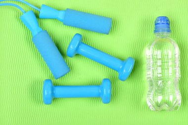 Halterler ve halat atlama su şişesinin yanında.