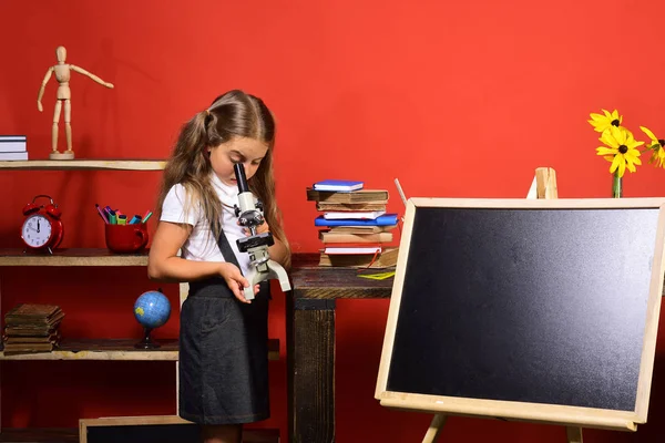 Estudante com cara ocupada na sala de aula. Menina olha para o microscópio — Fotografia de Stock