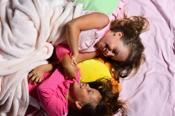 Colegialas en pijama rosa revolcarse en almohadas de colores, vista superior —  Fotos de Stock