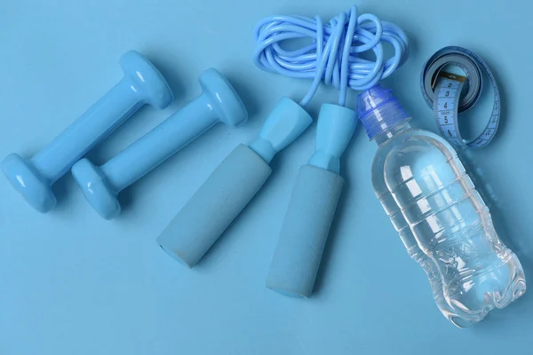 Flasche, Klebeband, Hantel und Springseil auf blauem Hintergrund. — Stockfoto