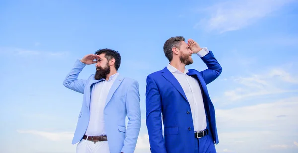 Changing course. New business directions. Developing business direction. Businessmen bearded faces stand back to back sky background. Men formal suit managers looking at opposite directions