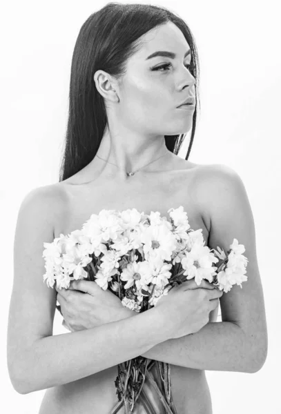 Menina no rosto calmo fica nua e mantém flores de camomila na frente do peito. Conceito de saúde da pele. Mulher com pele lisa e saudável parece atraente. Senhora cobre seios com flores, isoladas em branco — Fotografia de Stock