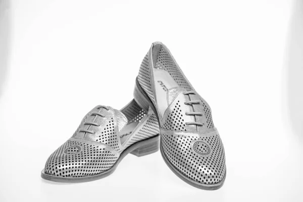 Zapatos hechos de cuero plateado sobre fondo blanco, aislados. Calzado para mujer en suela plana con perforación. Concepto de calzado femenino. Par de zapatos holgazanes cómodos de moda —  Fotos de Stock