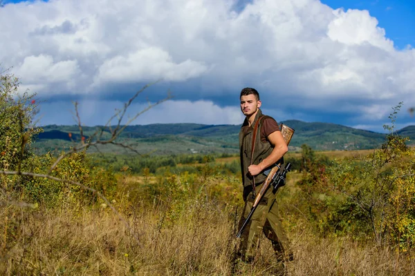 Regeling van de jacht. Man gespierde brutale man jachtopziener natuur achtergrond. Hunter geweer staat op de top van de berg. Een man met een baard jaagt op vogels. Jachthobby concept — Stockfoto