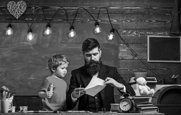 Child and teacher on busy face painting, drawing. Talented artist spend time with son. Teacher with beard, father teaches little son to draw in classroom, chalkboard on background. Art lesson concept — Stock Photo, Image