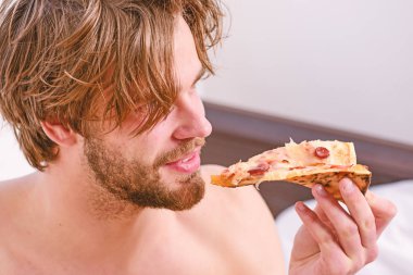 Gıda teslim Servisi. Seksi erkek yatakta yatarken pizza yemek. Genç adam bir çıplak ve pizza ile evde istirahat. Yatakta pizza yemek.