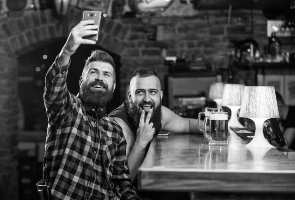 Send selfie to friends social networks. Man in bar drinking beer. Take selfie photo to remember great evening in pub. Online communication. Man bearded hipster hold smartphone. Taking selfie concept