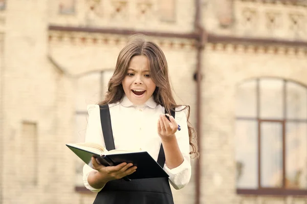 Schreiben Sie weiter. Glückliches kleines Mädchen mit Lehrbuch und Schreibstift im Freien. Kleines Schulkind beim Schreiben. Verbessern Sie Ihre Schreibfähigkeiten — Stockfoto