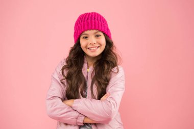 Havası ne olursa olsun. Sıcak kış kıyafetleri içinde neşeli bir çocuk. Çocuklar için mevsimlik moda. Küçük pembe duvar. kız kabarık ceket ve örgü şapka. Soğuk havada sağlık hizmeti. Mutluluk dolu
