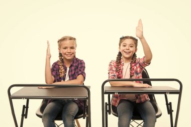 Ücretsiz veya özel eğitim. Küçük çocuklar ev eğitiminden keyif aldı. Zorunlu okullama yapan küçük kız öğrenciler. Beyaz üzerinde izole masalar oturan yükseltilmiş eller ile sevimli çocuklar. Okullama yılları