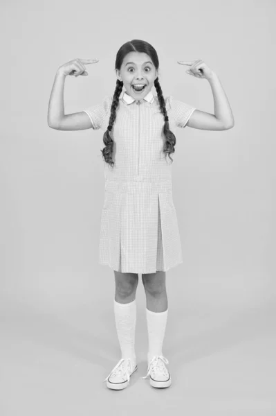 Surpresa e feliz. criança em estilo vintage apontando para o cabelo. Velha escola. moda infantil. criança feliz na parede amarela. moda e beleza. felicidade infantil. menina pequena em uniforme escolar. olhar retro — Fotografia de Stock