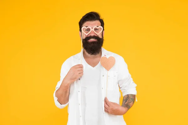 Juste heureux. homme brutal avec la barbe tomber amoureux. rendez-vous romantique. hipster masculin souriant dans des lunettes de fête. barbu homme hipster fond jaune. coeur d'amour pour les vacances de la Saint-Valentin. joyeux anniversaire — Photo