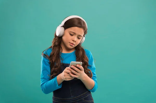 Читання текстового повідомлення. блог в сучасному житті. школярка використовує нову технологію. жити у віртуальному світі. дитина в навушниках. маленька дитина пише повідомлення на смартфоні. маленька дівчинка тримає мобільний телефон — стокове фото
