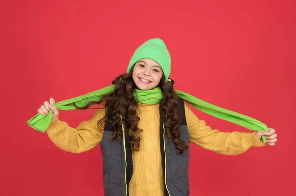 섹시 한 스카프는 따뜻 함을 위한 거야. 행복 한 어린이는 모자를 쓰고 긴 스카프를 착용 한다. 어린 소녀는 손에 스카프를 들고 미소짓는다. 겨울용 패션 액세서리. 화려 한 색깔의 아름다운 스카프 — 스톡 사진