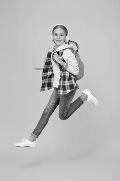 Sempre em movimento. Enérgico alegre adolescente ouvindo música. Estudante elegante indo para a escola. Menina pequena menina da moda levar mochila. A vida diária da escola. Feliz criança despreocupada. Escola e lazer — Fotografia de Stock