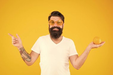 Sağlıklı beslenme alışkanlıkları hayatı teşvik eder. Hipster turuncu işaret parmak uzakta sarı arka plan üzerinde. Sakallı adam organik gıda yemeyi tercih. Doğal yeme planınızı uygulamaya koyun. Akıllı beslenme