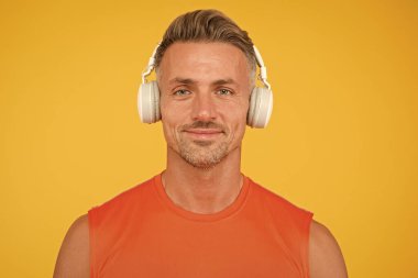 Kablosuz modern. Temiz ses. Modern teknoloji. Olgun adam, müzik dinle kablosuz cihaz sarı arka plan. Hippi modern kablosuz kulaklık kullanmaktan mutlu. Özgürlük kablosuz çalışıyor. Ses Defteri
