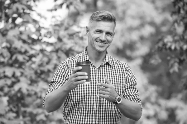 Dono de uma plantação de café. Homem bebendo xícara de papel de café. Mais um gole de café. A beber café em movimento. Relaxe e recarregue. Bonito alegre sorridente cara apontando para copo natureza fundo — Fotografia de Stock