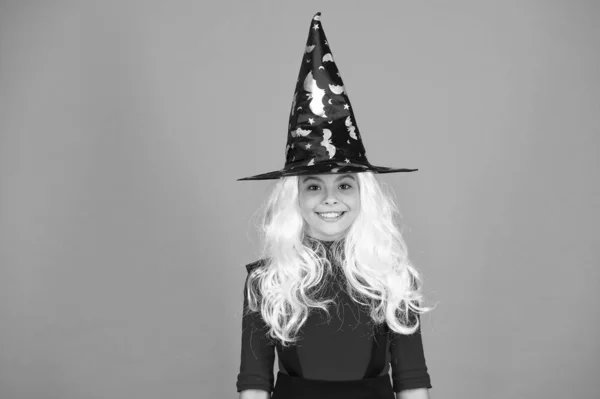 Ünnepi hangulatban. Varázslatos. Mosolygó lány halloween party. Rejtélyes boszorkány. Kisgyerek boszorkány kalap. Csokit vagy csalunk. természetfeletti elbűvölő ősz haj. gyerek varázslónő narancs háttér. Boldog Halloweent! — Stock Fotó