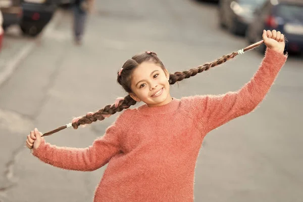 Criança sorriso no rosto bonito ao ar livre. Pequena menina feliz trançado penteado. Conceito de bom humor. Menina bonita com aparência fresca e pele. Dia internacional das crianças. Feliz infância. Feliz e positivo — Fotografia de Stock