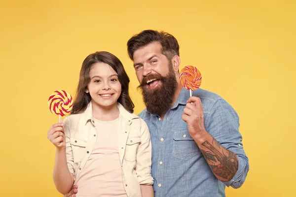 Snoep en traktaties concept. Dochter en vader eten zoete snoepjes. Lieve kindertijd. Meisje kind en papa houden kleurrijke lollies. Zoete dessert. Bearded hipster goede papa voor schattige dochter — Stockfoto