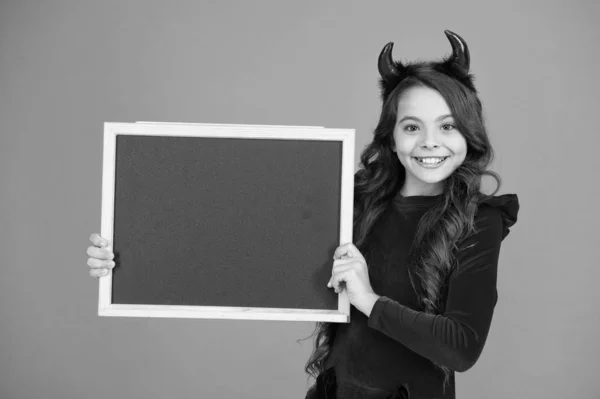 Performing her creativity. welcome to carnival party. happy halloween. autumn holiday sales. copy space. small girl school blackboard. little imp red horns. smiling kid info board. have fun