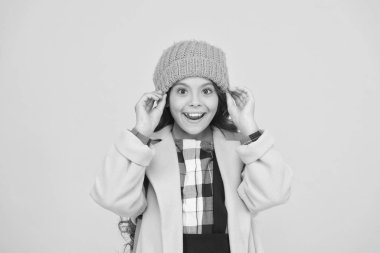 Kışlık şapka aksesuarı. Kız uzun saçlı sarı arka plan. Soğuk mevsim konsepti. Kış moda aksesuarı. Sıcak şapka takan küçük bir çocuk. En şirin ve en trend ler arasında seçim yapın. Çocuk kız örme şapka giymek