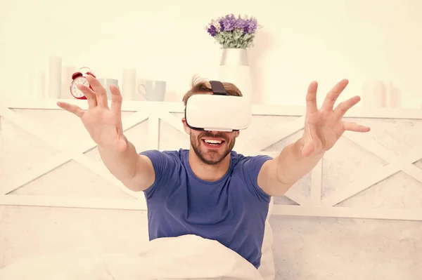 Utilizzo della tecnologia informatica per creare un ambiente simulato. Un ragazzo felice con le cuffie VR per i videogiochi. Un bell'uomo che gioca ai videogiochi virtuali a letto. Computer di gioco — Foto Stock