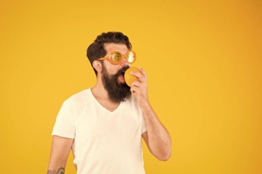 Taze ve sağlıklı. Sulu meyveler. Yaz beslenmesi. Yaz havasında sakallı hipster. Sarı arka planda turuncu güneş gözlüklü adam sakallı hipster. Olgun meyveli neşeli adam. Yaz tatili