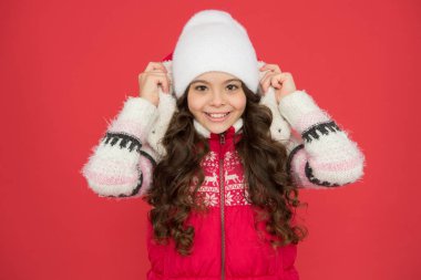 Cold weather. Winter fashion. Small girl long curly hair. Winter holidays ideas. Winter activity for kids. Happy childhood. Child in woolen knitted hat. Kids tend to feel cold more than adults clipart