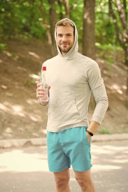 Susuz kalma. Sporcu parktaki eğitimden sonra su içer. Sporcu kıyafetleri su dengesini önemser. Sağlıklı bir yaşam tarzı. Vitamin ve mineraller. Sporcu adam elinde şişe suyu tutuyor.