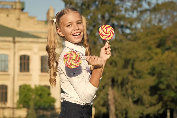 Glückliches Kind mit süßen Süßigkeiten. glückliche Kindheit. Kind mit Lutschbonbons. Süßigkeiten und Dessert-Konzept. glückliches Kind mit Süßigkeiten im Freien Spaß haben. Schulmädchen entspannen sich an sonnigen Tagen. Schulernährung — Stockfoto