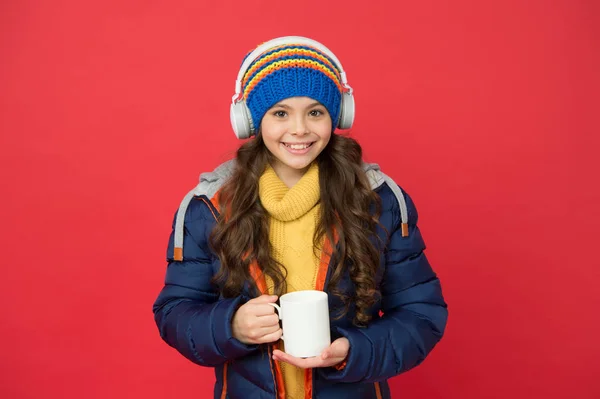 Mi serve solo caffe 'e forse della musica. Felice bambino tenere la tazza di caffè sfondo rosso. Alla bambina piace bere caffè. Bevanda calda. Freddo invernale. Nuove tecnologie. La vita moderna. Musica e caffè rendono la mia giornata — Foto Stock