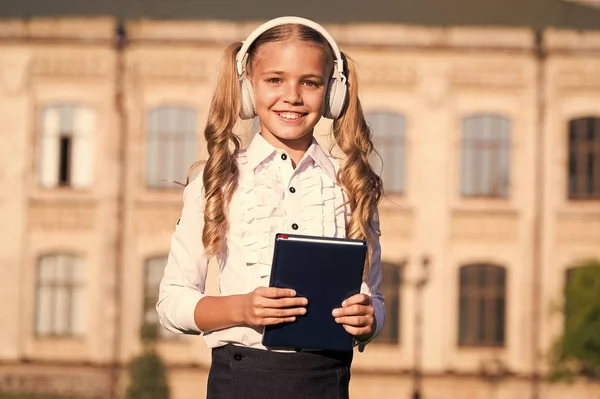 Luisteren schoolboek. Digitale technologieën voor leren. ELearning en moderne methodes. Meisje schattig schoolmeisje houden boek en hoofdtelefoon. Kennis assimileren beter op deze manier. Audio boek concept — Stockfoto
