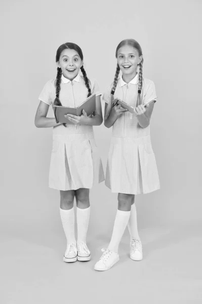 Interesse sincero. Meninas com enciclopédia ou livros infantis. Biblioteca da escola. Livros educativos para a escola. A ler livros. Lendo e recontando. Crianças pequenas segurando livros fundo amarelo — Fotografia de Stock