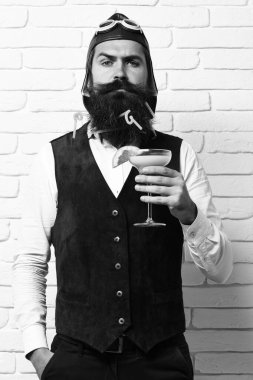 Beyaz tuğlalı arka planda yakışıklı, sakallı bir pilot.