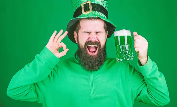 Dricka pints grön öl. Irländska mannen med skägg gestikulerande ok till öl. Skäggig man skåla för att saint patricks dag. Firar saint patricks dag i bar. Hipster i leprechaun hatt hålla ölglas — Stockfoto