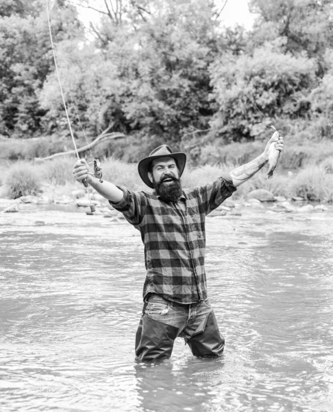 Pasatiempo masculino Fisher. La pesca requiere que usted sea consciente y totalmente presente en el momento. Equipo de pesca Fisher. Pescado en gancho. Hombre brutal usar botas de goma de pie en el agua del río. Pescador satisfecho — Foto de Stock