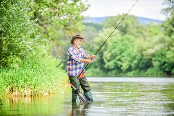 Homem maduro pescando. Lazer masculino. Pescador com cana de pesca. Felicidade é vara em sua mão. Pescador reformado. Homem sênior pegando peixe. Atividade e hobby. Pesca lago de água doce lagoa rio — Fotografia de Stock